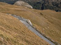 a steep winding road winds up into the mountains of scotland, which is covered with brown grass