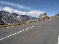 a man riding a skateboard down a road next to a rock formation and mountains