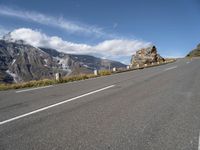 a man riding a skateboard down a road next to a rock formation and mountains