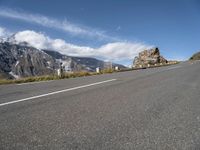 a man riding a skateboard down a road next to a rock formation and mountains