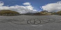 two mountains with some black circles on the road, and a bench in front of the mountain