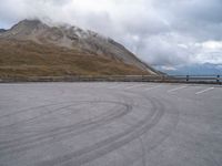 a parking lot with two people skateboarding on the road outside of the mountain scene