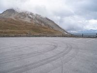 a parking lot with two people skateboarding on the road outside of the mountain scene