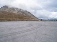 a parking lot with two people skateboarding on the road outside of the mountain scene