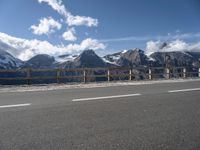 a van with snow - capped mountains in the background on a road side with railing