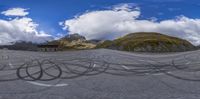 two mountains with some black circles on the road, and a bench in front of the mountain