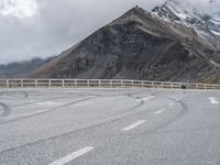 a person riding a motorcycle on the road near mountains and clouds that can be seen