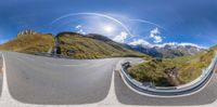 360 - pan photo of curved mountain road taken from camera angle with sun shining through clouds