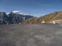 an empty parking lot with mountains in the background and a bird flying high above it