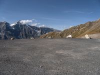 an empty parking lot with mountains in the background and a bird flying high above it