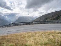 a person riding a motorcycle on a curvy road under stormy skies and clouds