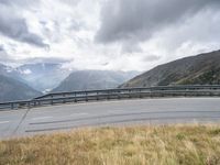 a person riding a motorcycle on a curvy road under stormy skies and clouds