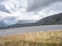 a person riding a motorcycle on a curvy road under stormy skies and clouds