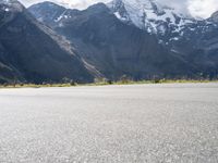 an image of a skateboarder skating on the road in front of snow capped mountains