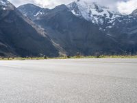 an image of a skateboarder skating on the road in front of snow capped mountains