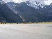 an image of a skateboarder skating on the road in front of snow capped mountains