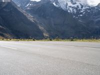 an image of a skateboarder skating on the road in front of snow capped mountains