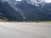 an image of a skateboarder skating on the road in front of snow capped mountains