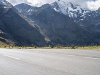 an image of a skateboarder skating on the road in front of snow capped mountains