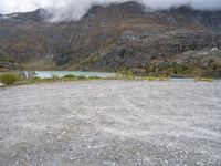 a mountain side with some very large mountains near a river and clouds above it, and a sign that says don't stop there