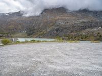 a mountain side with some very large mountains near a river and clouds above it, and a sign that says don't stop there