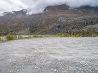 a mountain side with some very large mountains near a river and clouds above it, and a sign that says don't stop there