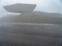 a building surrounded by a mountain of rubble on top of a highway in the fog