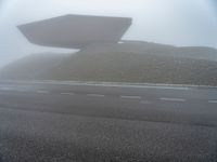 a building surrounded by a mountain of rubble on top of a highway in the fog