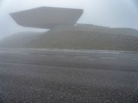 a building surrounded by a mountain of rubble on top of a highway in the fog