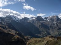 the mountaintop with a cow grazing next to a mountain range covered in snow and brown grass