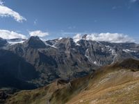 the mountaintop with a cow grazing next to a mountain range covered in snow and brown grass