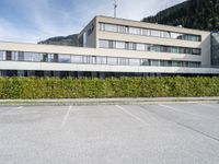 an office building with windows and shrubbery lining the sides of the street outside of it