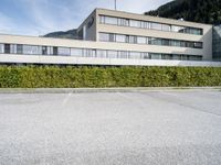 an office building with windows and shrubbery lining the sides of the street outside of it