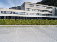 an office building with windows and shrubbery lining the sides of the street outside of it