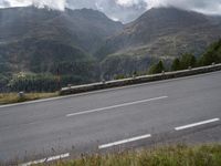 a lone motorcycle is travelling down the road on a mountain pass in front of some mountains