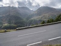 a lone motorcycle is travelling down the road on a mountain pass in front of some mountains