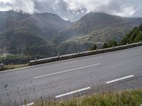 a lone motorcycle is travelling down the road on a mountain pass in front of some mountains