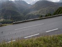 a lone motorcycle is travelling down the road on a mountain pass in front of some mountains