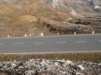 a motorcycle riding on top of a gravel road near rocks and mountains for cyclists to ride