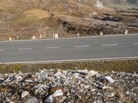 a motorcycle riding on top of a gravel road near rocks and mountains for cyclists to ride