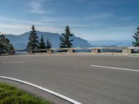 a motorcycle traveling down the road by the water and mountains near it in switzerland, europe