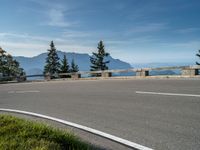 a motorcycle traveling down the road by the water and mountains near it in switzerland, europe