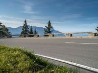 a motorcycle traveling down the road by the water and mountains near it in switzerland, europe