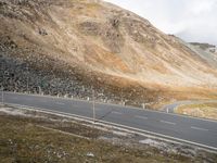 a motorcycle is riding on an empty road in the mountains, overlooking a mountain range