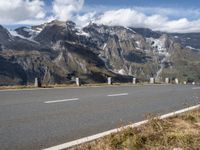 a motorcycle driving on a road between two mountains with a snow covered mountain in the distance