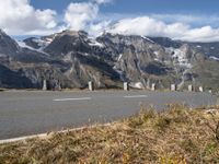 a motorcycle driving on a road between two mountains with a snow covered mountain in the distance