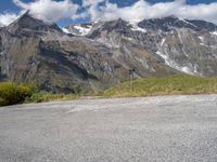 a person on a motorcycle on the road with mountains in the background and clouds in the sky