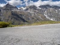 a person on a motorcycle on the road with mountains in the background and clouds in the sky