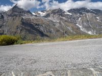 a person on a motorcycle on the road with mountains in the background and clouds in the sky