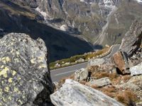 a motorcycle on a scenic mountain road with a rock in front of it and a valley below